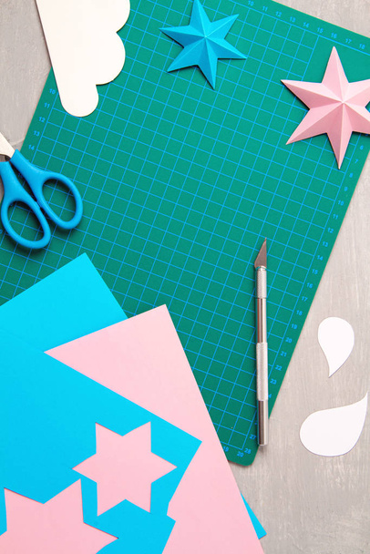 Top view over paper  cut tools, scissors, cutter, cutting mat, and crafted paper objects. DIY trendy project concept - 写真・画像