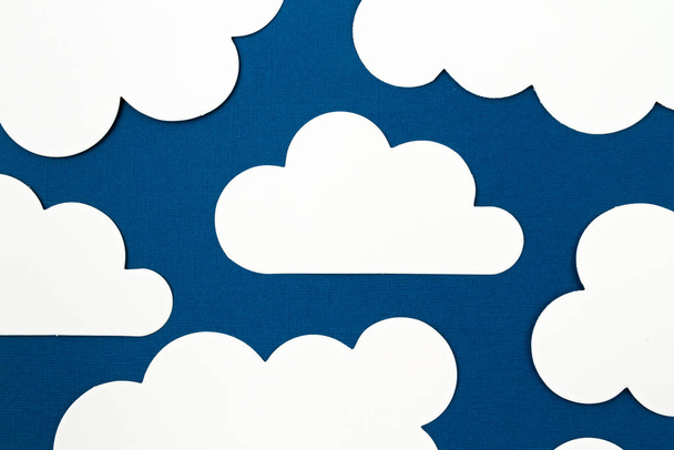 White paper cut out clouds over blue background. - Foto, Bild