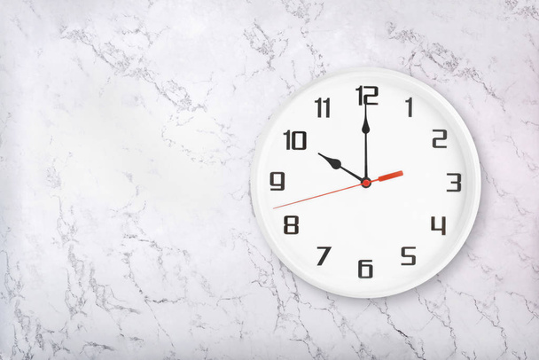 Orologio da parete rotondo bianco su sfondo bianco in marmo naturale. Dieci oclock
 - Foto, immagini