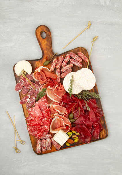 Appetizers table with differents antipasti, charcuterie, snacks and wine. Sausage, ham, tapas, olives, cheese and crackers for buffet party - Foto, imagen