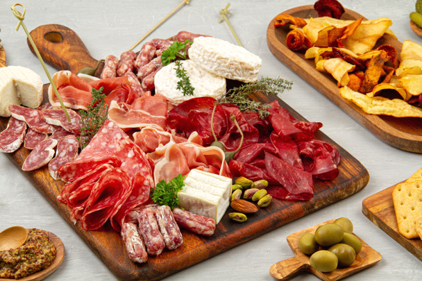 Τραπέζι ορεκτικών με διάφορα antipasti, charcuterie, σνακ και κρασί. Λουκάνικα, ζαμπόν, τάπας, ελιές, τυρί και κράκερ για μπουφέ - Φωτογραφία, εικόνα