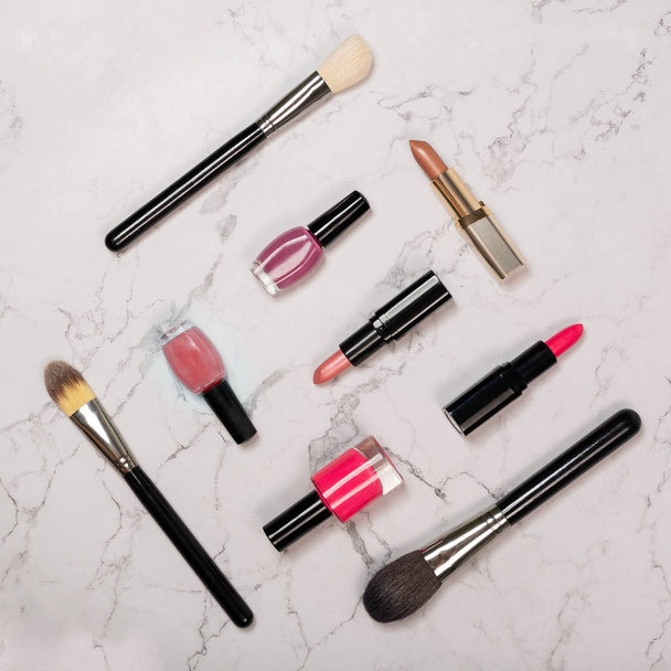 Flat lay of cosmetic products including lipsticks, nail varnish, makeup brushes - Photo, image