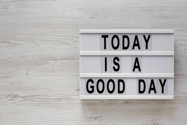 "Σήμερα είναι μια καλή μέρα" λέξεις σε ένα σύγχρονο διοικητικό συμβούλιο σε ένα λευκό ξύλινο  - Φωτογραφία, εικόνα