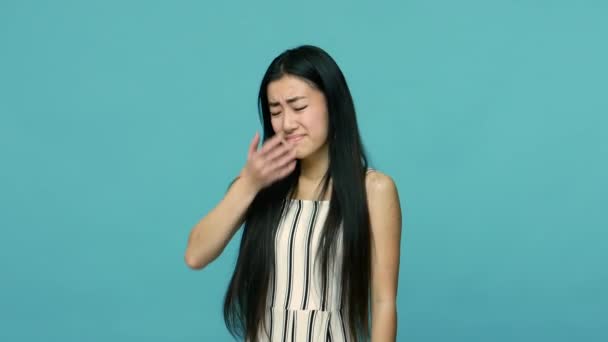 No, i don't want to watch. Asian woman with long black hair covering face and showing stop gesture, refusing to watch, hiding eyes, ignoring problems. indoor studio shot isolated on blue background - Záběry, video