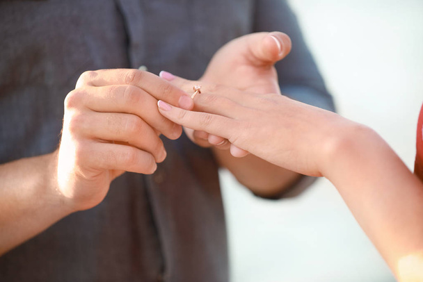 Young man putting ring on finger of his fiancee after marriage proposal, closeup - Foto, Imagem
