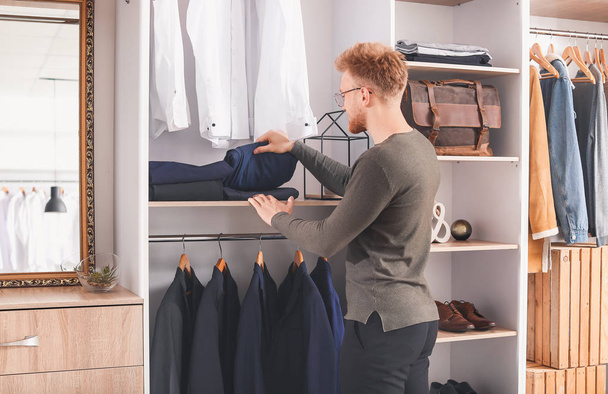 Handsome man choosing clothes in dressing room - Zdjęcie, obraz