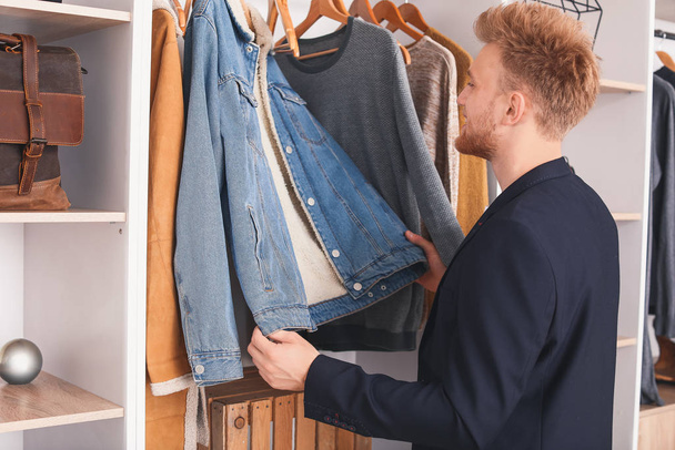 Handsome man choosing clothes in dressing room - Photo, Image