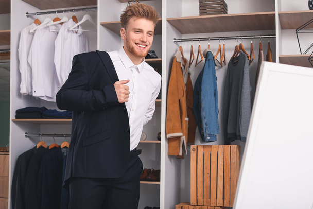 Knappe man probeert stijlvolle kleren in de kleedkamer - Foto, afbeelding