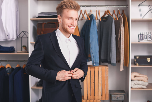 Hombre guapo probándose ropa elegante en el vestidor
 - Foto, Imagen