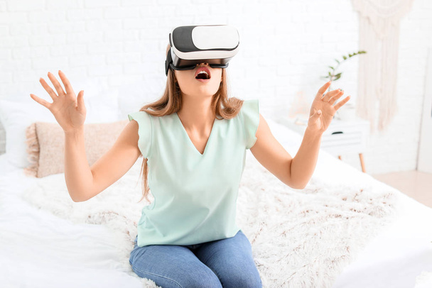 Young woman with virtual reality glasses at home - Foto, afbeelding
