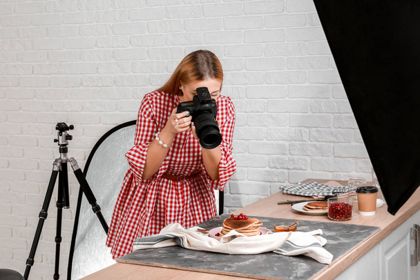 Jonge vrouw neemt foto van pannenkoeken in professionele studio - Foto, afbeelding