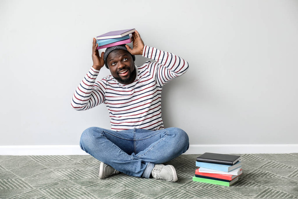 Αφροαμερικάνος με βιβλία κοντά σε ανοιχτό τοίχο - Φωτογραφία, εικόνα