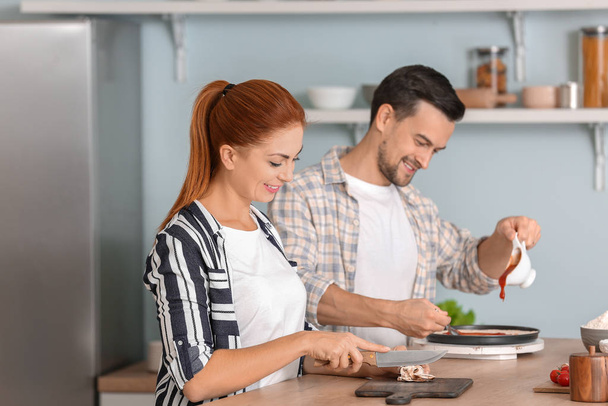 Happy couple cooking together in kitchen - Foto, imagen