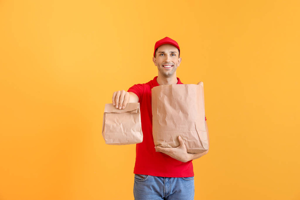 Handsome worker of food delivery service on color background - Photo, Image