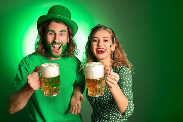 Νεαρό ζευγάρι με μπύρα στο φόντο του χρώματος. Γιορτή του Αγίου Πατρικίου - Φωτογραφία, εικόνα