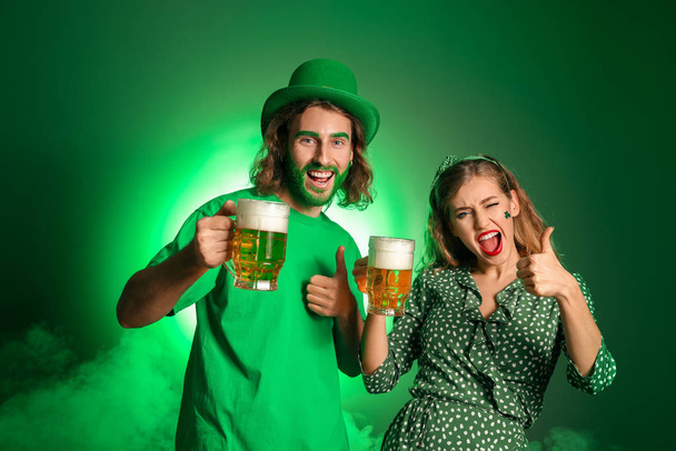 Νεαρό ζευγάρι με μπύρα στο φόντο του χρώματος. Γιορτή του Αγίου Πατρικίου - Φωτογραφία, εικόνα