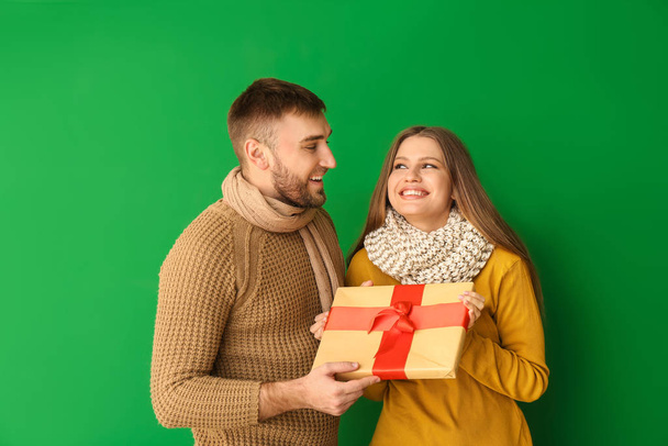 Happy man giving present to his girlfriend against color background - Zdjęcie, obraz