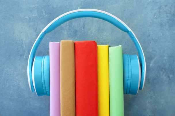 Bücher und moderne Kopfhörer auf farbigem Hintergrund. Hörbuchkonzept - Foto, Bild