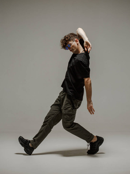 Guy dancing contemporary dance in studio. Neutral grey background. Acrobatic bboy dancer. - Foto, Imagen