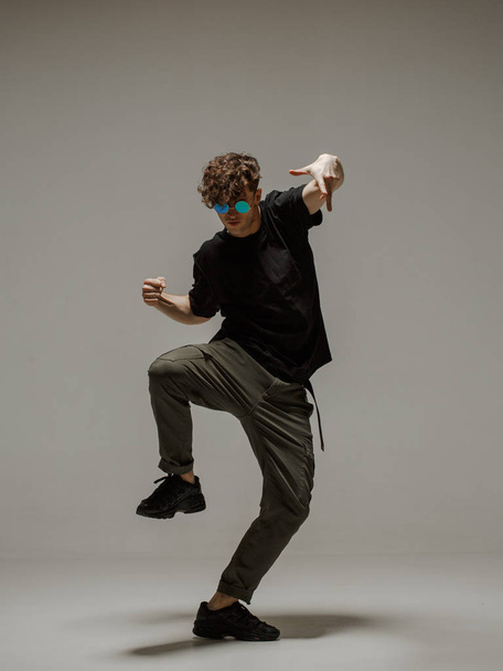 Guy dancing contemporary dance in studio. Neutral grey background. Acrobatic bboy dancer. - Fotoğraf, Görsel