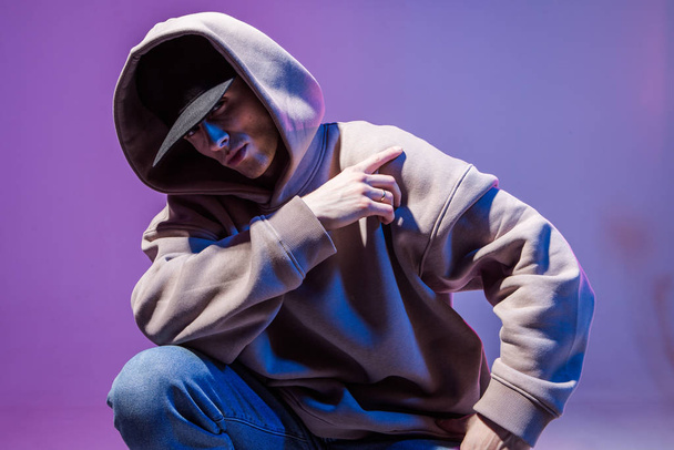 Modern Epic portrait of bboy in a neon light hoodie. Beneath the hood. Dark face. Mysterious and cool. - Foto, Imagen