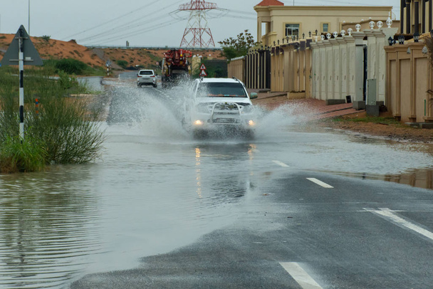 LKW fährt durch Hochwasser auf der Straße und macht große Wasserspritzer in Wohngebiet. - Foto, Bild