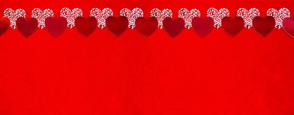 Red and white Valentine hearts on a bright red velvet background are located on top. Lots of space for text. Valentines day greeting card and long banner. Top view. Copy space. Heart lives love - Foto, Bild