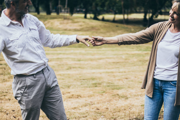 Krásný senioři usměvavý pár muž a žena tančí v parku v romantické chvíli. Vřelé manželství a milenecké pouto a vztah. Manžel a žena zamilovaní. Fotky šťastných důchodců - Fotografie, Obrázek