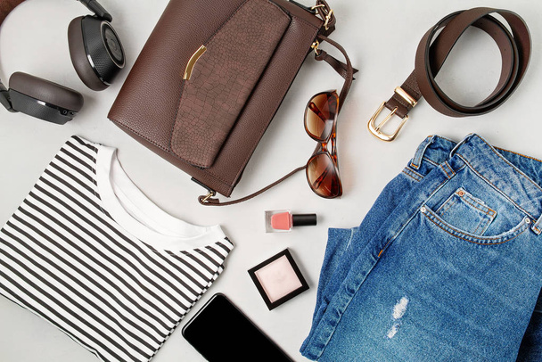 Female fashion accessories, jeans, sunglasses, smart phone, earphones and handbag. Beauty, urban outfit and fashion concept - Photo, Image
