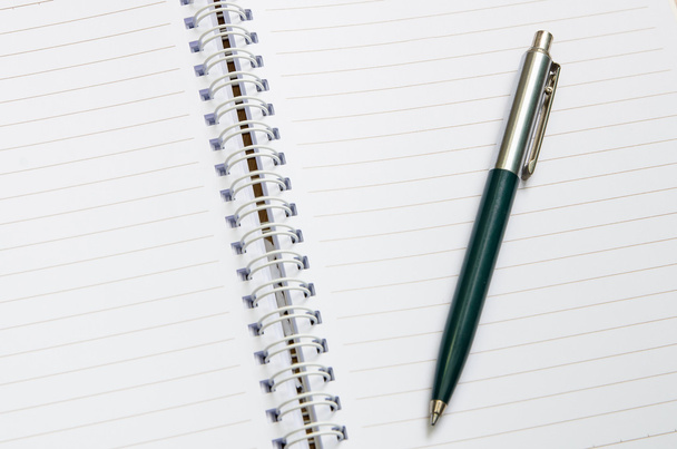 klassieke pen zetten op nieuwe pagina van notebook - Foto, afbeelding