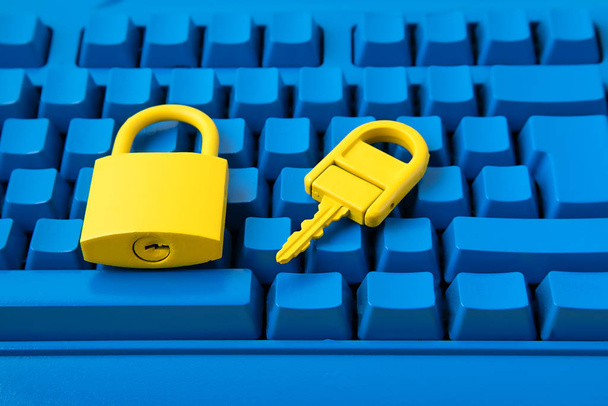 Cyber data and information security idea. Yellow padlock and key and blue keyboard. Computer, information safety, confidentiality concept - Photo, Image