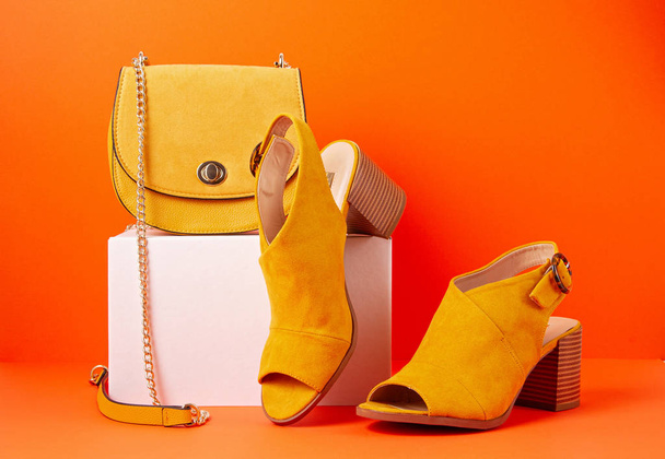 Gelbe Damenmodeaccessoires, Schuhe und Handtasche auf orangefarbenem Hintergrund. Schönheit, Shopping, urbanes Outfit und Modetrends - Foto, Bild