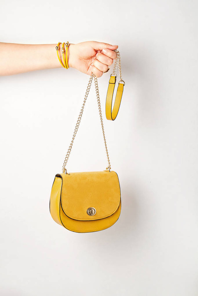Mujer mano sosteniendo accesorios de moda femenina amarilla, bolso de mano. Belleza, compras, atuendo urbano y tendencias de la moda
 - Foto, imagen