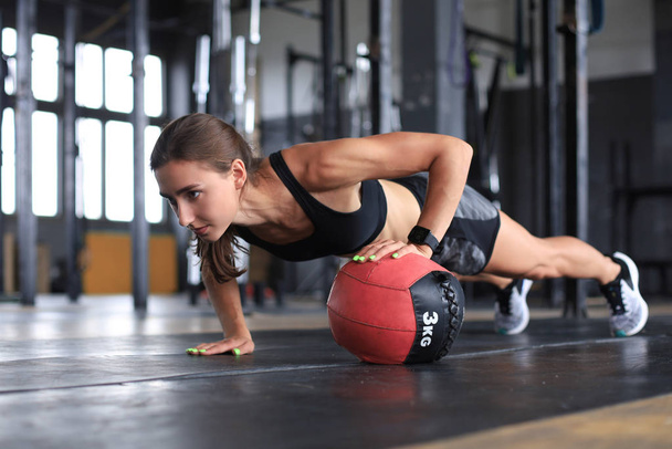 Fit and muscular woman exercising with medicine ball at gym. - Fotó, kép