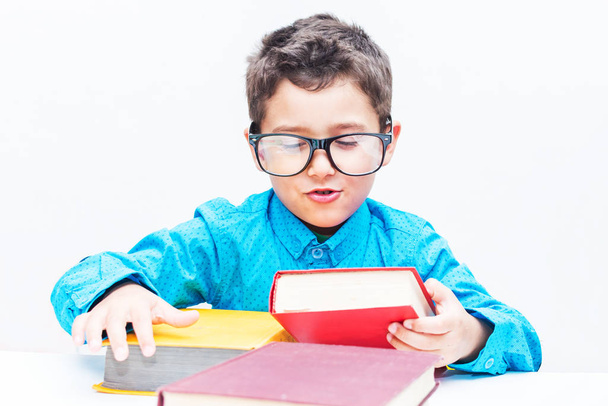 mignon garçon dans des lunettes assis à un bureau avec des livres
 - Photo, image