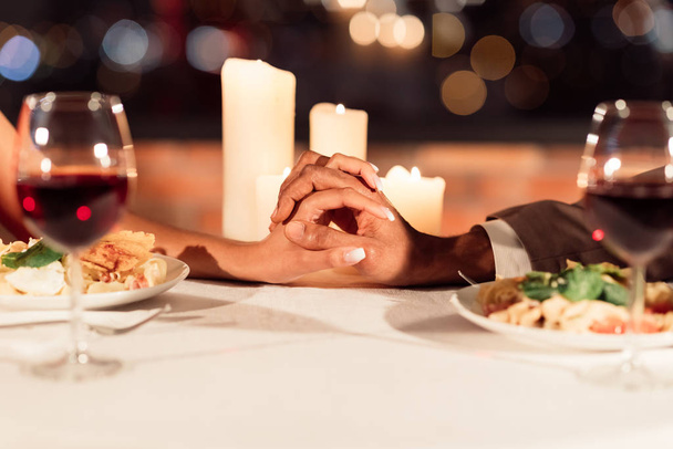 Homem e mulher segurando as mãos na mesa no restaurante, close-up
 - Foto, Imagem