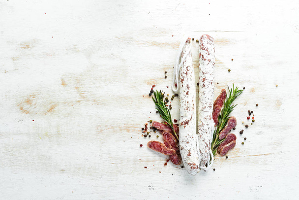 Fuet, a traditional Spanish sausage with rosemary. Slice sausages. Rosemary. Top view. Free space for your text. - Fotografie, Obrázek