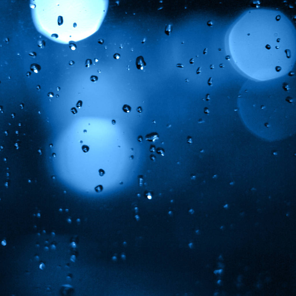 Blurred city lights with rain drops foreground. Unfocused colorful lights behind glass with drops. Shiny lights of night bokeh.. - Photo, image