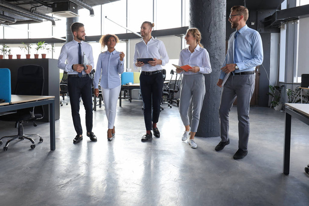Οι σύγχρονοι επιχειρηματίες έχουν μια συζήτηση ενώ περπατούν στο γραφείο - Φωτογραφία, εικόνα