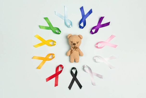 Toy bear with circle of  colorful awareness ribbons on blue back - 写真・画像