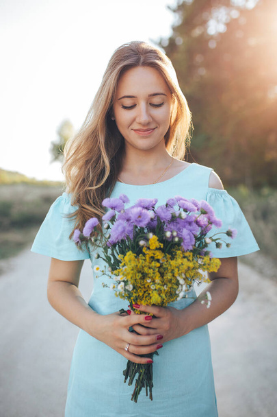 Young girl holding a bouquet of wildflowers - Фото, изображение