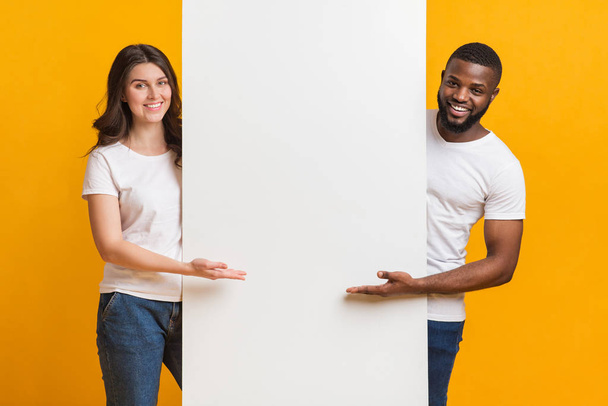 Sorrindo Multiracial casal segurando e apontando para White Advertisement Board
 - Foto, Imagem