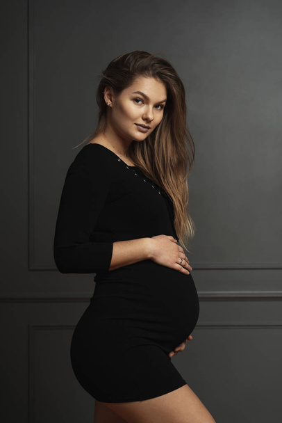 Портрет великолепная молодая беременная женщина прикосновение нежно руками ее живот, она ждет новую жизнь
 - Фото, изображение