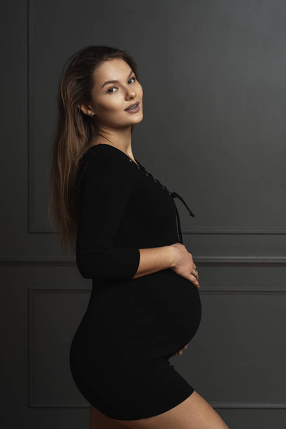 Portre muhteşem genç hamile kadın ellerini karnıyla hafifçe dokunmadan, o yeni bir hayat bekliyor - Fotoğraf, Görsel