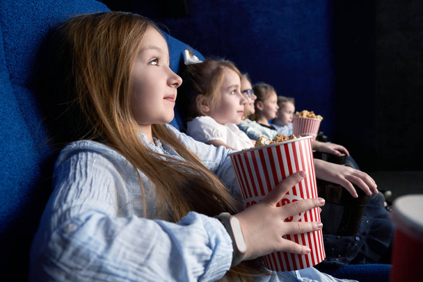Side view of pretty girl watching film in cinema - Foto, afbeelding