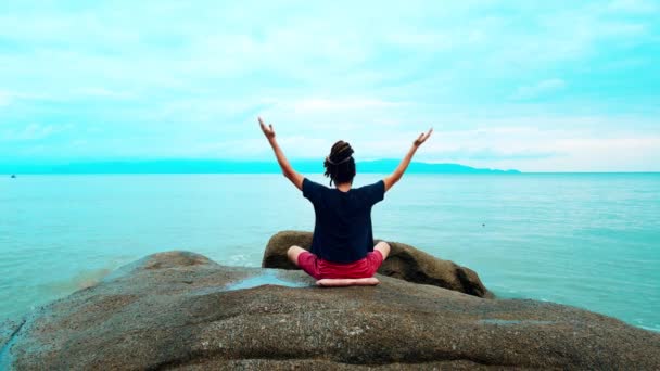 Yogi meditiert am Meer. ein Mann mit Dreadlocks in der Lotusposition - Filmmaterial, Video