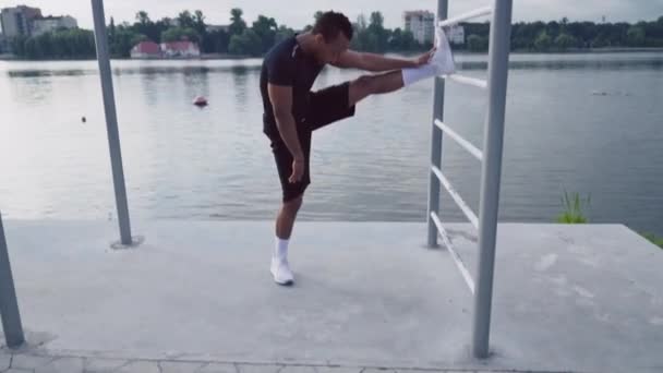 Full length portrait of african guy stretching leg near lake - Filmmaterial, Video