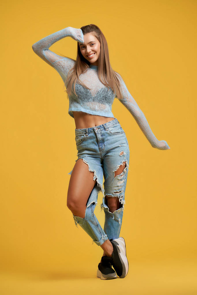 Smiling girl crossing legs, raising hand - Foto, afbeelding