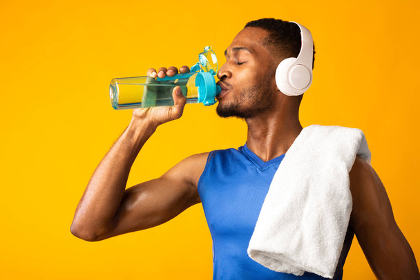 Afro-Sportler trinkt Wasser und hört Musik - Foto, Bild