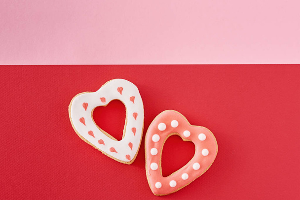 Cookies de forma de coração decorados em um fundo vermelho e rosa colorido, vista superior
 - Foto, Imagem